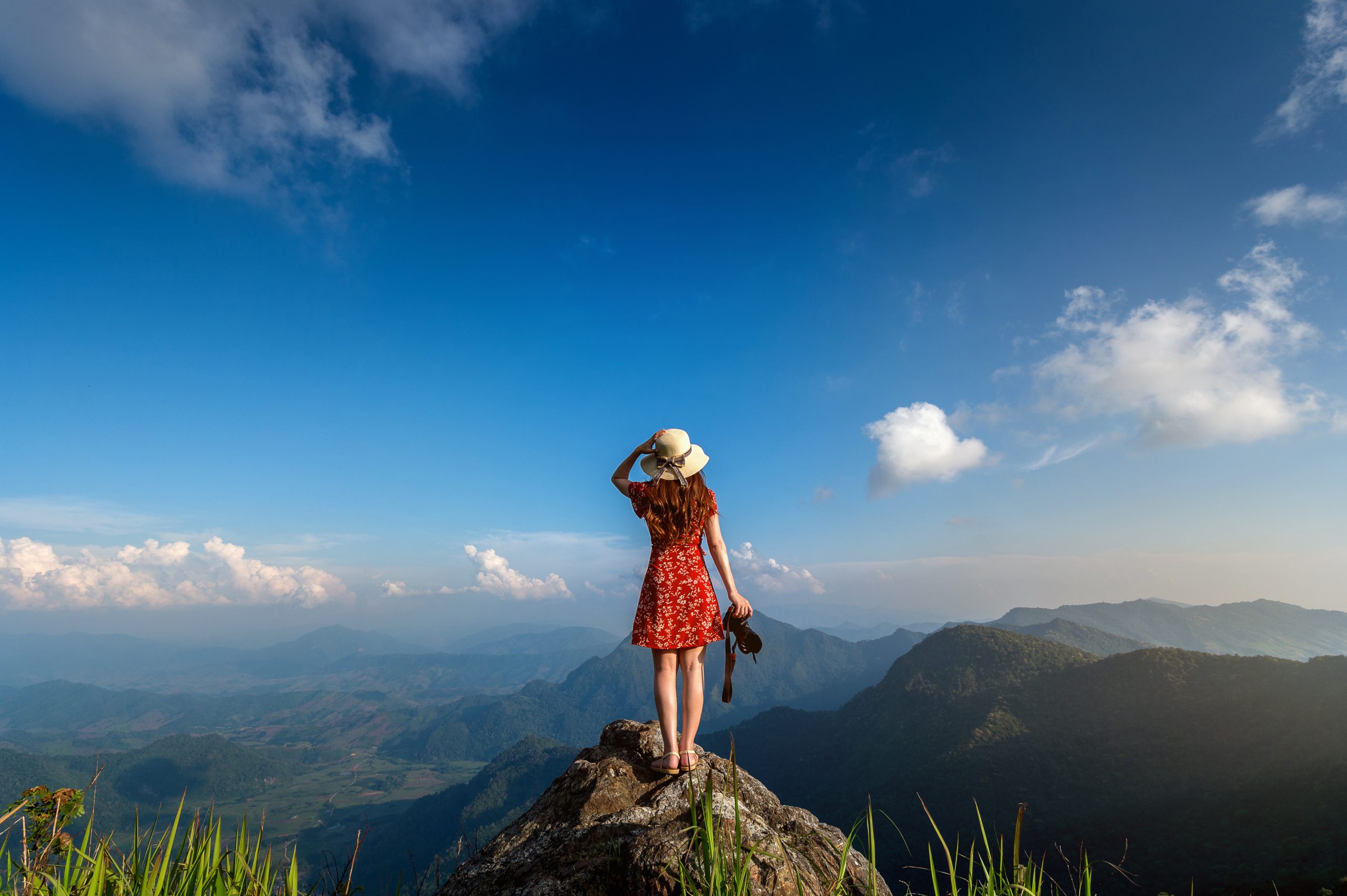 Woman hand holding camera and standing on top of the rock in nat
